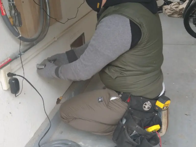 Electrician performing outlet wiring in a Ludlow garage